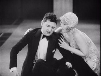 Movie still from “The Broadway Melody” (1929), directed by Harry Beaumont – A man and a woman in formal wear are sitting on the ground; Medium shot, Low angle