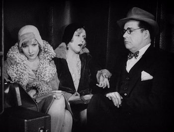 Movie still from “The Broadway Melody” (1929), directed by Harry Beaumont – A group of people sitting on top of a couch; Medium shot, Over the shoulder angle