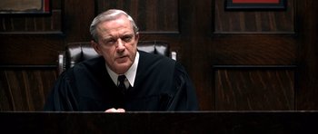 Movie still from “Ali” (2001), directed by Michael Mann – An older man in a judge's robe sitting in a courtroom; Close Up shot, Low angle