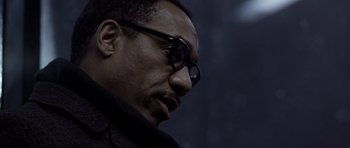 Movie still from “Ali” (2001), directed by Michael Mann – A person wearing glasses and a jacket; Close Up shot, Low angle