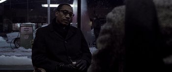 Movie still from “Ali” (2001), directed by Michael Mann – A man in a black coat is sitting next to a white dog; Close Up shot, Over the shoulder angle