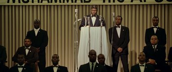 Movie still from “Ali” (2001), directed by Michael Mann – A group of men standing around a microphone; Medium shot, Low angle