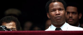 Movie still from “Ali” (2001), directed by Michael Mann – A man that is standing in front of a microphone; Close Up shot, Low angle