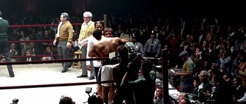 Movie still from “Ali” (2001), directed by Michael Mann – A crowd watching a boxing match in a boxing ring; Wide shot, Over the shoulder angle