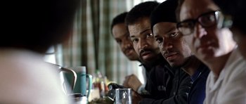 Movie still from “Ali” (2001), directed by Michael Mann – A group of men sitting at a table with drinks; Close Up shot, Over the shoulder angle