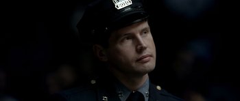 Movie still from “Ali” (2001), directed by Michael Mann – A police officer in uniform looking to his left; Close Up shot, Over the shoulder angle