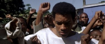 Movie still from “Ali” (2001), directed by Michael Mann – A man in a crowd of people raising their hands; Close Up shot, Low angle