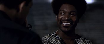 Movie still from “Ali” (2001), directed by Michael Mann – A person with a smile on their face; Close Up shot, Low angle