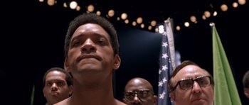 Movie still from “Ali” (2001), directed by Michael Mann – A man standing in front of a group of people; Close Up shot, Low angle