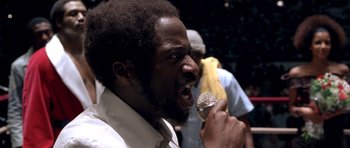 Movie still from “Ali” (2001), directed by Michael Mann – A man with a beard is singing into a microphone; Close Up shot, Low angle