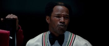 Movie still from “Ali” (2001), directed by Michael Mann – A person wearing a jacket and bow tie; Close Up shot, Low angle