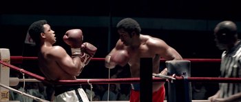 Movie still from “Ali” (2001), directed by Michael Mann – Two boxers in a boxing ring during a match; Medium shot, Over the shoulder angle