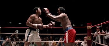Movie still from “Ali” (2001), directed by Michael Mann – Two boxers in a boxing ring with spectators in the background; Medium shot, Low angle