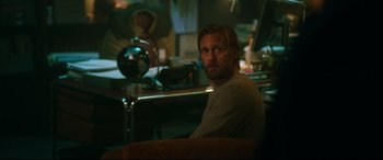 Movie still from “Godzilla vs. Kong” (2021), directed by Adam Wingard – A man sitting at a table in a room; Medium shot, Over the shoulder angle