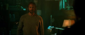 Movie still from “Godzilla vs. Kong” (2021), directed by Adam Wingard – A man standing in a dark room with a microphone; Medium shot, Over the shoulder angle