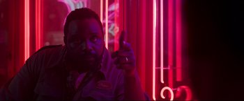 Movie still from “Godzilla vs. Kong” (2021), directed by Adam Wingard – A man is sitting in front of a neon sign; Close Up shot, Low angle