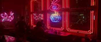Movie still from “Godzilla vs. Kong” (2021), directed by Adam Wingard – Two people sitting at a table in front of a neon sign; Extreme Wide shot, Over the shoulder angle