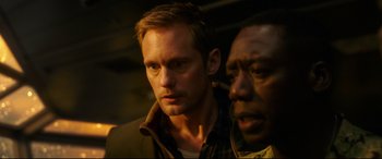 Movie still from “Godzilla vs. Kong” (2021), directed by Adam Wingard – A man standing next to another man in a dark room; Close Up shot, Over the shoulder angle