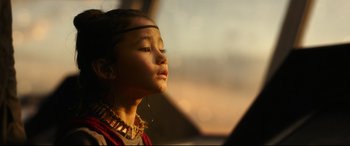 Movie still from “Godzilla vs. Kong” (2021), directed by Adam Wingard – A young girl wearing a necklace looking up at the sky; Close Up shot, Over the shoulder angle