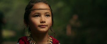 Movie still from “Godzilla vs. Kong” (2021), directed by Adam Wingard – A young native american girl wearing a headdress; Close Up shot, Over the shoulder angle
