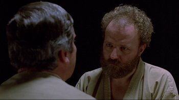 Movie still from “The Brood” (1979), directed by David Cronenberg – A man with a beard is looking at himself in the mirror; Close Up shot, Over the shoulder angle