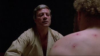 Movie still from “The Brood” (1979), directed by David Cronenberg – A man looking at himself in the mirror in front of a mirror; Close Up shot, Over the shoulder angle