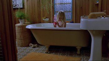 Movie still from “The Brood” (1979), directed by David Cronenberg – A little girl sitting in a bath tub holding a toothbrush; Wide shot, High angle
