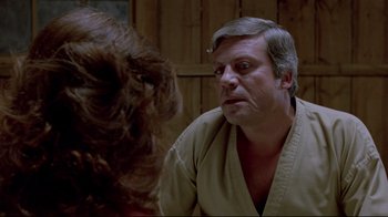 Movie still from “The Brood” (1979), directed by David Cronenberg – An older man in a white shirt is talking to a young woman; Close Up shot, Over the shoulder angle