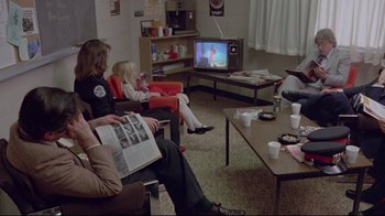 Movie still from “The Brood” (1979), directed by David Cronenberg – A group of people sitting in a living room watching television; Wide shot, High angle