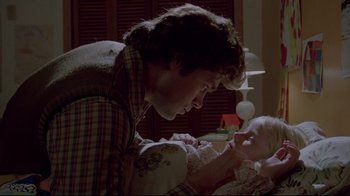 Movie still from “The Brood” (1979), directed by David Cronenberg – A man holding a baby in his arms and looking at it; Close Up shot, Low angle