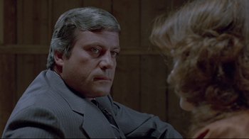Movie still from “The Brood” (1979), directed by David Cronenberg – A person wearing a suit and tie; Close Up shot, Over the shoulder angle