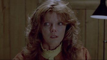 Movie still from “The Brood” (1979), directed by David Cronenberg – A person with long curly hair; Close Up shot, Low angle