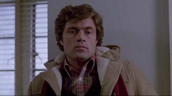 Movie still from “The Brood” (1979), directed by David Cronenberg – A person wearing a jacket and plaid shirt; Close Up shot, Low angle
