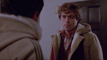 Movie still from “The Brood” (1979), directed by David Cronenberg – A young man looking into a mirror while wearing a jacket; Close Up shot, Over the shoulder angle