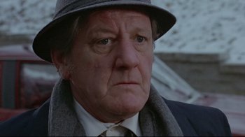 Movie still from “The Brood” (1979), directed by David Cronenberg – An older man wearing a hat and a tie; Close Up shot, Low angle