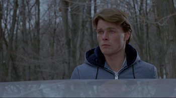 Movie still from “The Brood” (1979), directed by David Cronenberg – A young man in a gray jacket looking off into the distance; Close Up shot, Over the shoulder angle