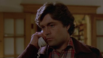 Movie still from “The Brood” (1979), directed by David Cronenberg – A man talking on a phone while wearing a plaid shirt; Close Up shot, Low angle