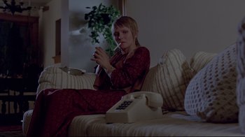 Movie still from “The Brood” (1979), directed by David Cronenberg – A woman smoking a cigarette while sitting on a couch; Medium shot, Low angle