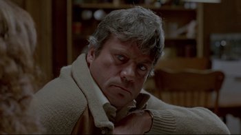 Movie still from “The Brood” (1979), directed by David Cronenberg – An older man wearing a sweater and looking at the camera; Close Up shot, Low angle