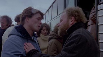 Movie still from “The Brood” (1979), directed by David Cronenberg – Two men standing next to each other in front of a bus; Close Up shot, Over the shoulder angle