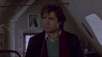 Movie still from “The Brood” (1979), directed by David Cronenberg – A man with long brown hair wearing a sweater and a scarf; Close Up shot, Low angle