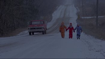 Movie still from “The Brood” (1979), directed by David Cronenberg – Two children are holding hands while walking down a snow covered road; Wide shot, High angle