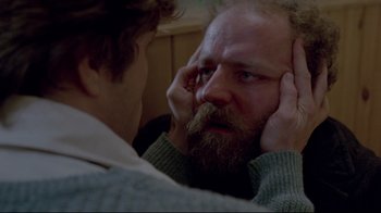 Movie still from “The Brood” (1979), directed by David Cronenberg – A man with a beard looking at himself in the mirror; Close Up shot, Over the shoulder angle