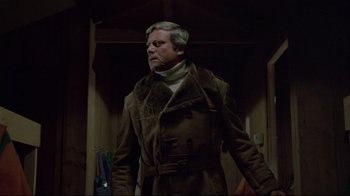 Movie still from “The Brood” (1979), directed by David Cronenberg – An older man wearing a brown coat and a white neck tie; Medium shot, Low angle