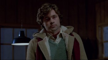 Movie still from “The Brood” (1979), directed by David Cronenberg – A man in a sweater and a sweater jacket; Medium shot, Over the shoulder angle