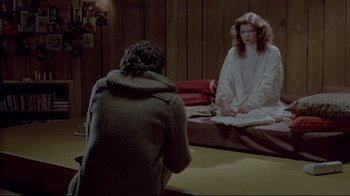 Movie still from “The Brood” (1979), directed by David Cronenberg – A woman sitting on the ground in front of a man; Wide shot, High angle