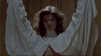 Movie still from “The Brood” (1979), directed by David Cronenberg – A woman in a white shirt is holding her arms up; Medium shot, Low angle