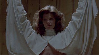 Movie still from “The Brood” (1979), directed by David Cronenberg – A woman in a white shirt and a white jacket; Medium shot, Low angle