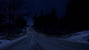 Movie still from “The Brood” (1979), directed by David Cronenberg – A car driving down a snowy road at night; Extreme Wide shot, High angle