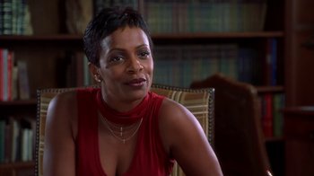 Movie still from “The Brothers” (2001), directed by Gary Hardwick – A woman sitting in a chair in front of a book case; Close Up shot, High angle
